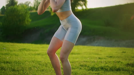 A-woman-squats-with-dumbbells-in-the-Park-at-sunset-performing-lunges-to-the-side.-Motivation-and-sports-training.-A-single-woman-does-exercises-at-sunset-in-the-summer